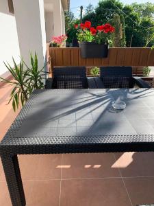 a black table and chairs on a patio with flowers at Puszta Hotel in Berekfürdő