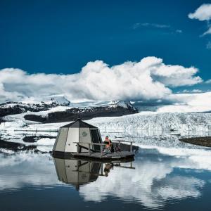 un hombre está sentado en un barco en el agua en Fjallsarlon - Overnight adventure, en Hof