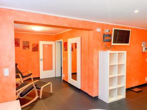 Camera con pareti arancioni, TV e sedie. di Ferienhaus Salzhaffblick a Rerik