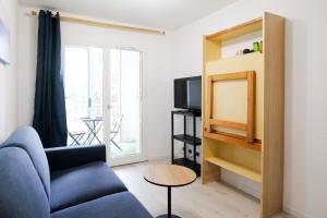 a living room with a blue couch and a tv at Studio au calme idéalement situé à Port Olona - La Chaume - 2 personnes in Les Sables-dʼOlonne