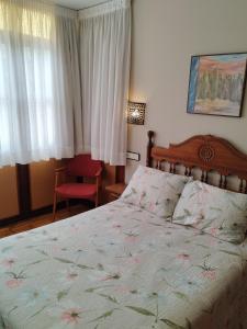Hotel Los Hidalgos في سانتيانا ديل مار: غرفة نوم بسرير كبير وكرسي احمر