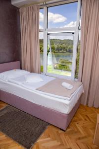 Cama en habitación con ventana grande en Motel New Sanatron, en Bosanski Novi