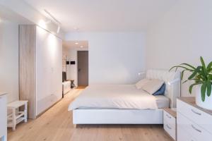 ein weißes Schlafzimmer mit einem weißen Bett und einer Pflanze in der Unterkunft Revalia Das Haus Studios in Tallinn