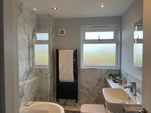 ein Badezimmer mit einer Badewanne, einem Waschbecken und einem WC in der Unterkunft Modern 3 Bed home in Grantham in Grantham