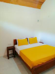 een bed met 2 gele kussens in een kamer bij Serenity Sinharaja in Deniyaya