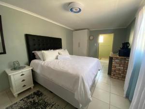 a bedroom with a white bed with a black headboard at Inecia's B & B in Uis