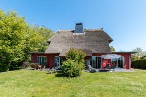 a red house with a thatched roof on a lawn at An den Boddenwiesen 02 in Wieck