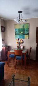 una mesa de comedor con un jarrón de flores. en Manuel Cortina 11, en Villaviciosa