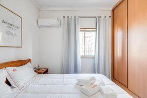 Un dormitorio con una cama blanca con toallas. en Hopstays - Almada Saudade en Almada