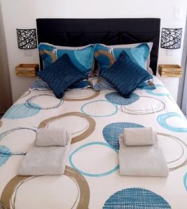 Una cama con almohadas azules encima. en Romytt Suite en Saint-Quentin-la-Poterie
