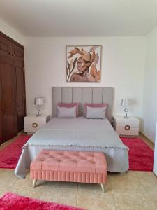 1 dormitorio con 1 cama grande con reposapiés rosa en Casa Branca Pinhal, en Nazaré