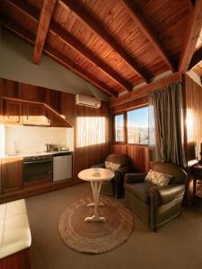 een woonkamer met een tafel en een keuken bij Las Bayas Home Suites in Esquel