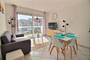 a living room with a couch and a table with chairs at Annonce professionnelle. T2 Cabine avec balcon, 4 personnes au cœur de la ville et à deux pas du sable chaud in Hardelot-Plage