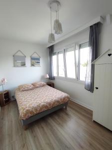 een slaapkamer met een bed in een kamer met ramen bij La Belle Vie Ouistreham Riva Bella Résidence Hastings in Ouistreham