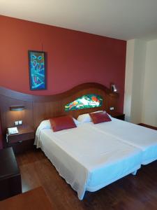 a bedroom with a large white bed with a red wall at Ohtels Mazagon in Mazagón