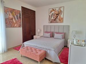 1 dormitorio con 1 cama grande y 1 reposapiés rosa en Casa Branca Pinhal, en Nazaré