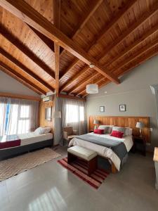 sypialnia z 2 łóżkami i drewnianym sufitem w obiekcie Las Bayas Home Suites w mieście Esquel