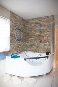 a white bath tub in a bathroom with a brick wall at Ferienwohnung Viola mit Wallbox in Schneverdingen