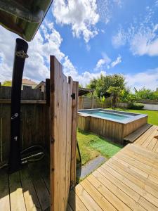 a wooden deck with a fence and a swimming pool at Spacieuse maison avec piscine, 9km de l'océan. in Tosse