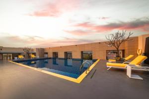 a swimming pool with yellow chairs and a building at Greenpark Hyderabad in Hyderabad