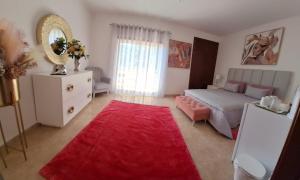 1 dormitorio con cama, espejo y alfombra roja en Casa Branca Pinhal, en Nazaré