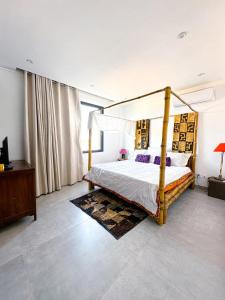 1 dormitorio con cama con dosel y TV en Résidence Théa, en Dakar