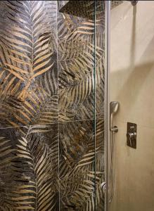 Una ducha con puerta de cristal con estampado de hojas. en Hercules Home Malia, en Malia