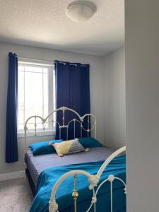 a bedroom with a bed with blue sheets and a window at Private room in Calgary*Netflix*TV*Wifi*Parking in Calgary