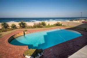 a swimming pool with the ocean in the background at Wavecrest in Umdloti