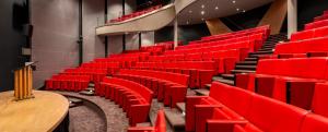 een leeg auditorium met rode stoelen en een tafel bij Fletcher Hotel-Restaurant Sparrenhorst-Veluwe in Nunspeet