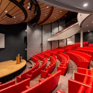 un auditorium vide avec des chaises rouges et une scène dans l'établissement Fletcher Hotel-Restaurant Sparrenhorst-Veluwe, à Nunspeet