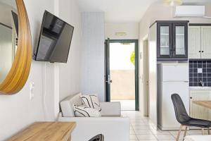a kitchen with a tv on the wall and chairs at Sunset Premium Studio C in Agios Nikitas