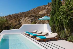 a group of lounge chairs with an umbrella next to a swimming pool at Nammos Hotel Mykonos in Psarou