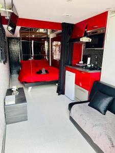 カップ・ダグドにあるAphrodiX Village naturisteの赤いベッドとキッチンが備わる客室です。