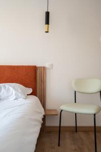 um quarto com uma cama e uma cadeira em Le Cottage du Louvre em Lens