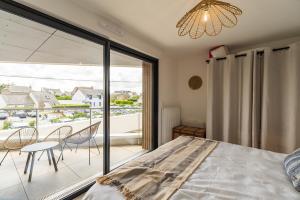 a bedroom with a view of a balcony with a bed and chairs at Les terrasses de Ploumanac'h 150m de la plage in Perros-Guirec
