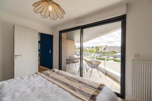 a bedroom with a bed and a view of a balcony at Les terrasses de Ploumanac'h 150m de la plage in Perros-Guirec