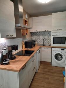 cocina con armarios blancos, lavadora y secadora en Appartement AB DU PARC en Neufchâtel-Hardelot