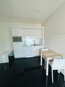 una cocina con armarios blancos y una mesa y sillas de madera. en B&B Monti, en Porto Cesareo