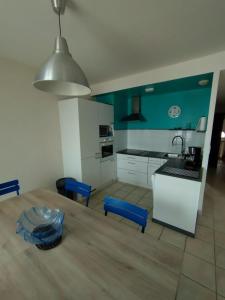 キブロンにあるappartement vue merの青い壁のキッチン(木製テーブル付)