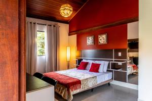 a bedroom with a bed with a red wall at Pousada Rainha da Mata in Penedo