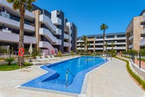 una piscina di fronte a un edificio con palme di Apartmán v luxusním komplexu Flamenca Village a Orihuela Costa