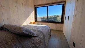 a bedroom with a bed and a large window at Casa MacaFelipe in Pichilemu