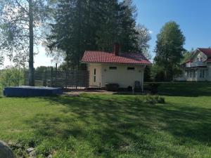 een klein wit huis met een rood dak bij Viihtyisä saunamökki päärakennuksen takana, oma rauha in Nivala +6 foto's