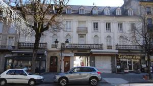twee auto's geparkeerd op een straat voor een gebouw bij Appart T4 Luchon plein centre in Luchon
