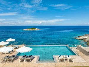 a swimming pool with chairs and umbrellas and the ocean at Il sogno di Zante in Skinária