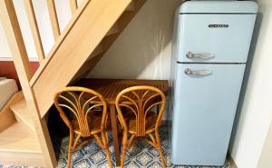 een oude koelkast met drie stoelen naast een trap bij Voyage à Little Havana in Bouguenais