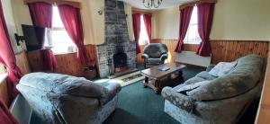 a living room with two chairs and a fireplace at Fanore Holiday Cottages in Ballyvaughan