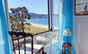 a window with a chair and a view of a beach at Apartamento con vistas al mar en la playa de Vilagarcia - O Feitizo in Vilagarcia de Arousa
