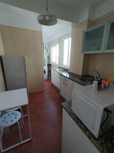 a kitchen with white cabinets and a red tile floor at Apartamento Diputación 25 in Nerja